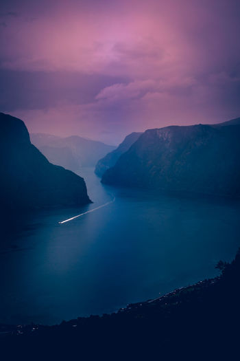 Scenic view of lake amidst mountains against dramatic sky