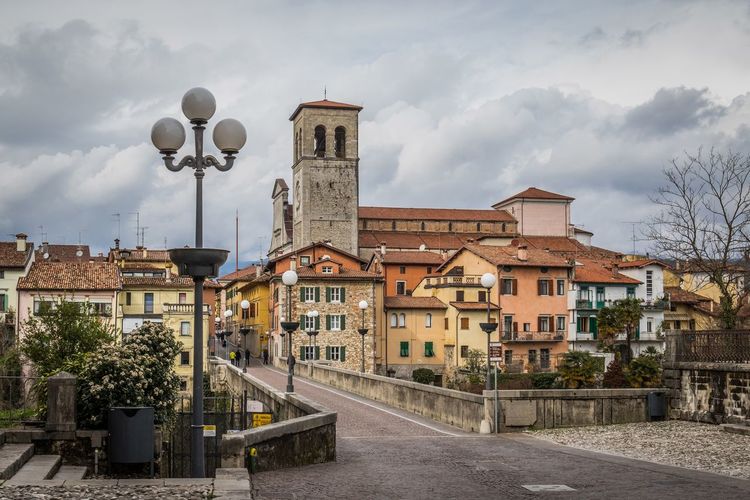 Empty road amidst buildings against cloudy sky