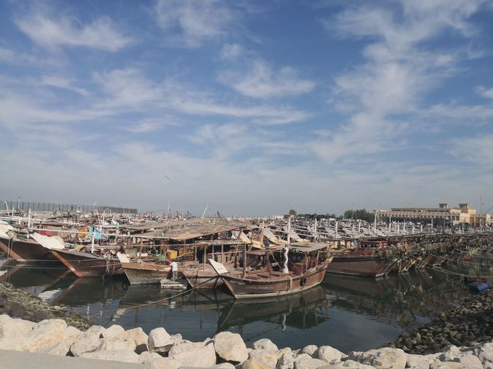 Old boats called dhow moored at harbor against sky