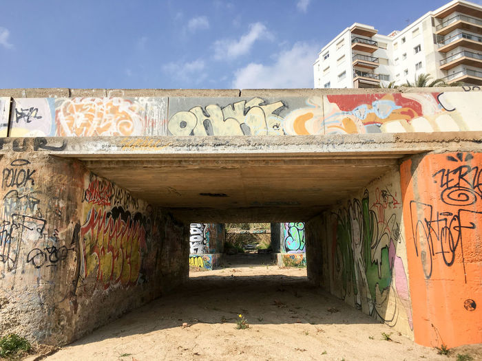 Graffiti on tunnel by building against sky