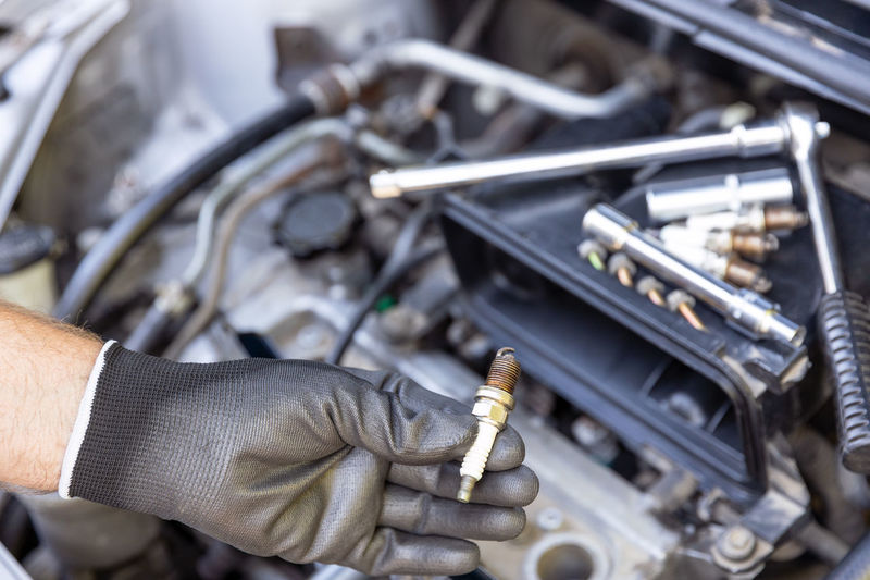 Cropped hand of man repairing car engine