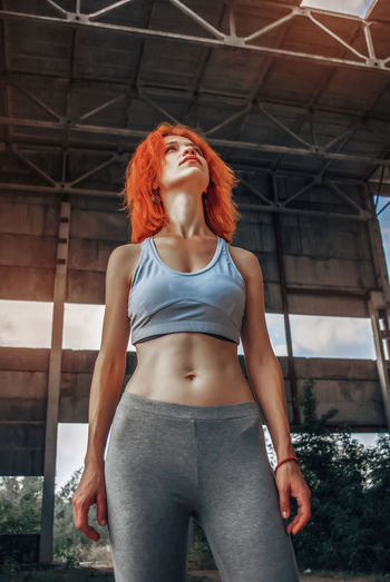 Strong female athlete wearing sportswear taking break after exercising. fit woman standing