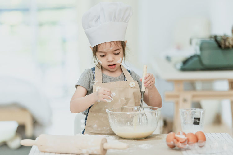 Girl holding ice cream in bowl on table