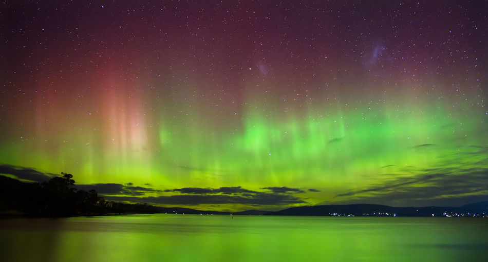 Scenic view of aurora australis southern lights over lake against sky at night