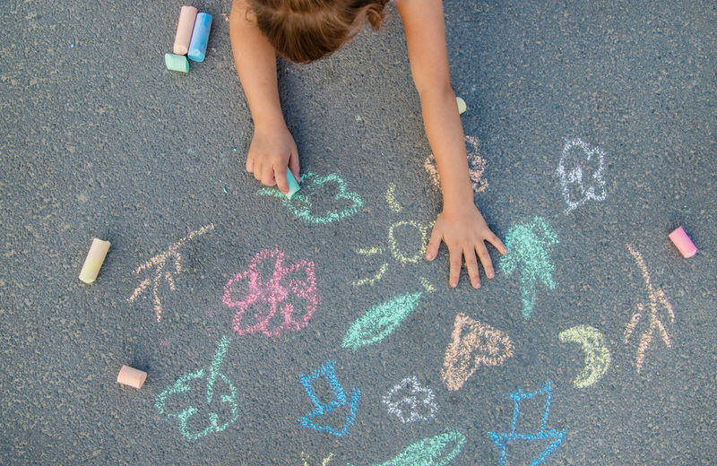 Girl drawing with chalk on footpath