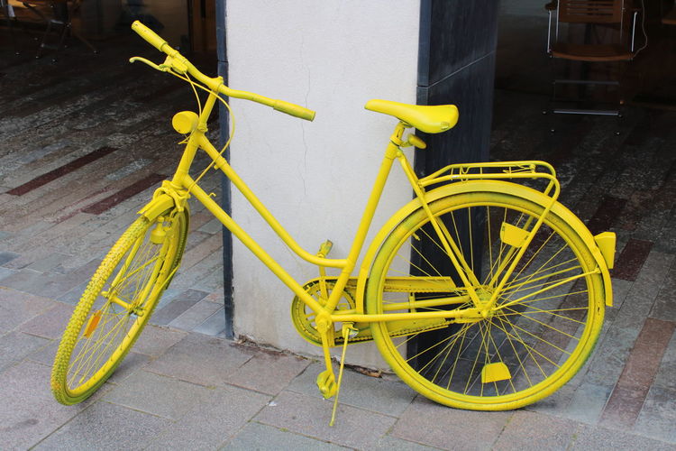 Yellow bicycle parked on street.