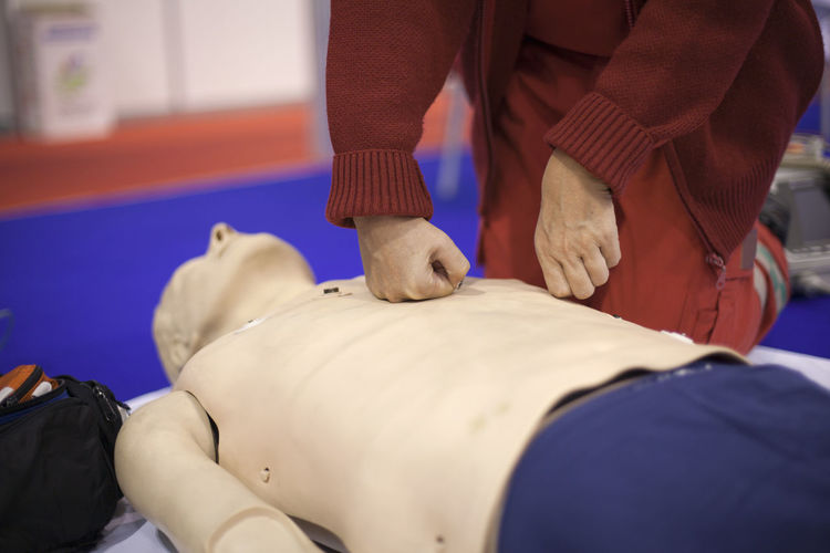 Midsection of man practicing on cpr dummy at hospital