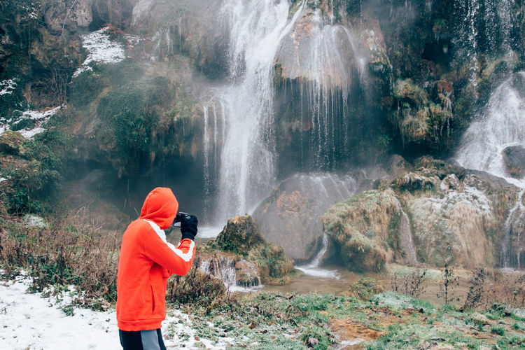 Side view of hiker photographing waterfall