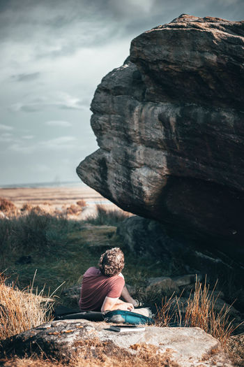 Man lying on rock against sky