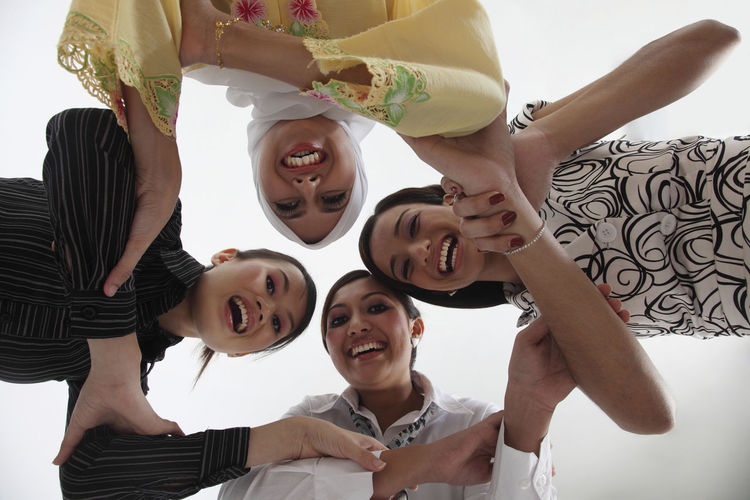 Low angle view of female friends huddling against white background