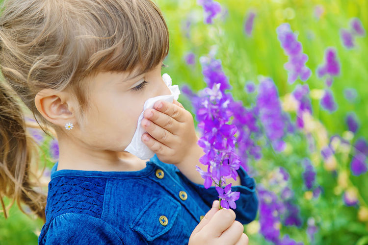 Close-up of girl wiping nose with tissue