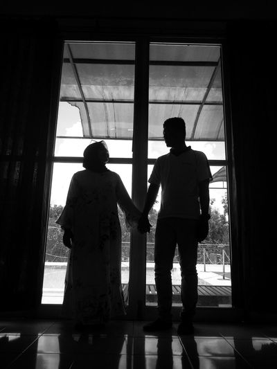 Rear view of silhouette people standing against window