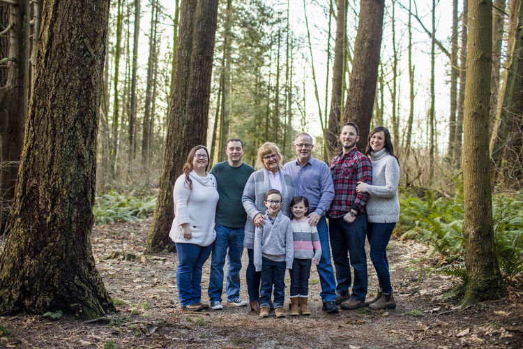 Happy family standing for photo in a forested park.