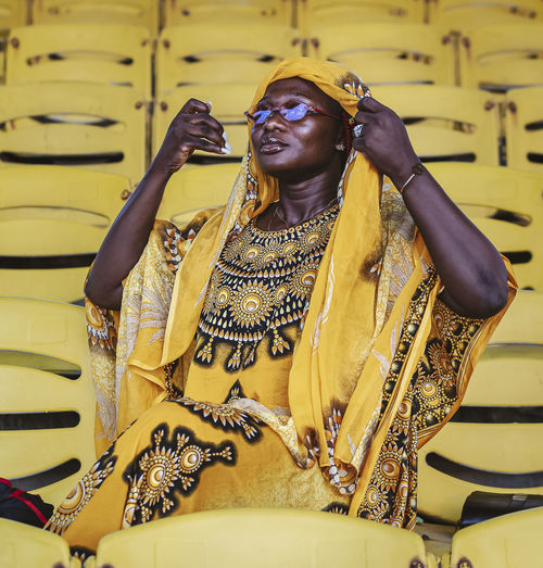 African woman in yellow suit sitting in an empty grandstand on independence square in accra ghana 