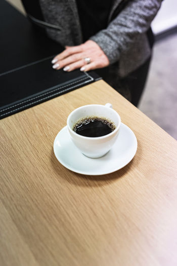 Midsection of woman holding coffee on table