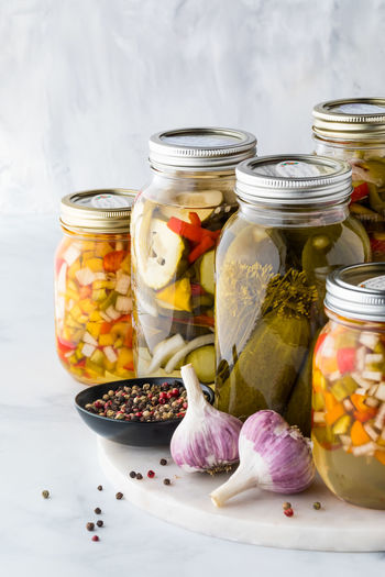 Jars of homemade pickles and pickled peppers against a light background.