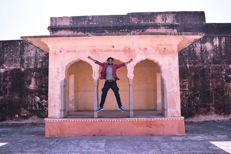 Full length of carefree young man jumping at historic site