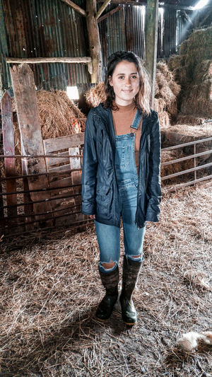 Portrait of a smiling young woman standing inside a barn