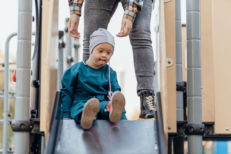 A boy, person with down syndrome walks in the park with his mother, spinning on the carousel