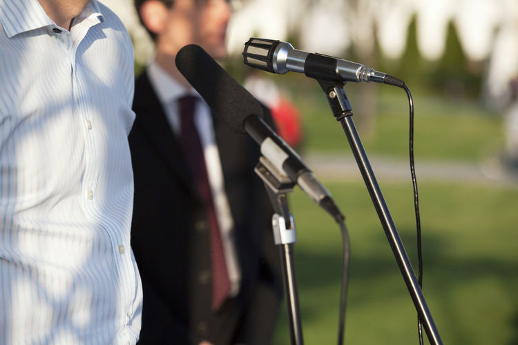 Midsection men standing in front of microphones