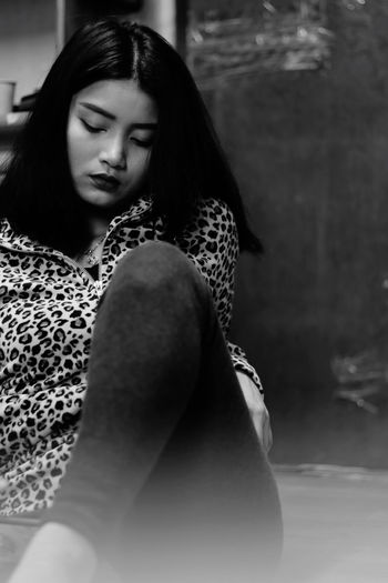 Young woman looking away while sitting outdoors