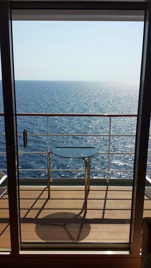 Scenic view of sea against clear sky seen from glass door in cruise ship