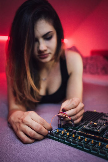 Seductive woman repairing circuit board while lying on bed at home