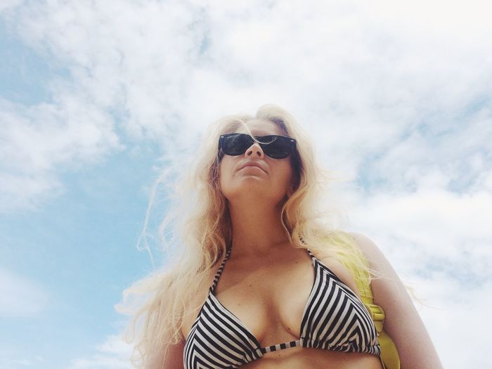 Low angle view of woman wearing bikini against cloudy sky