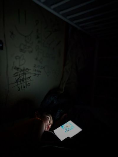Boy sleeping on bed in darkroom