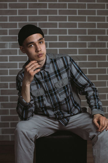 Young man sitting against wall