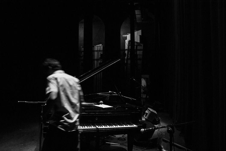 Man standing by piano in darkroom