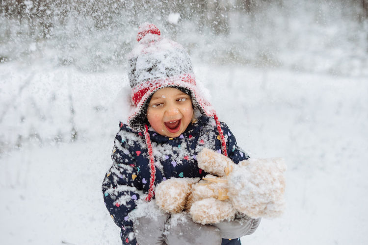 Happy child covered in snow playing outdoors.
