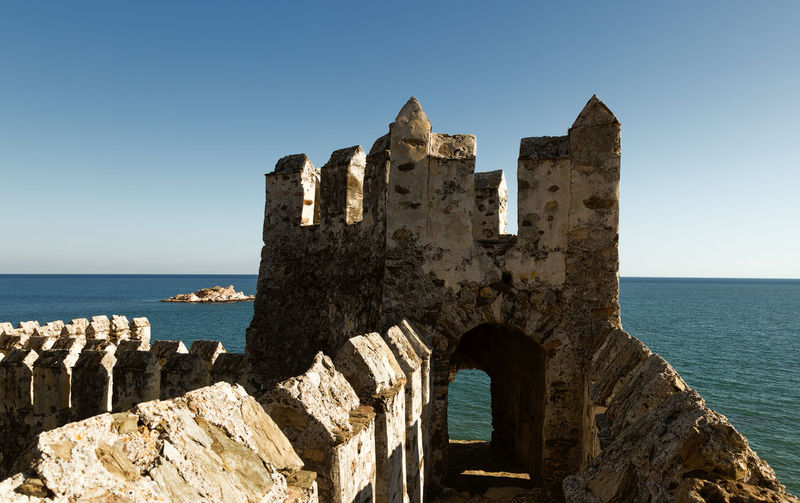 Old ruin by sea against clear sky