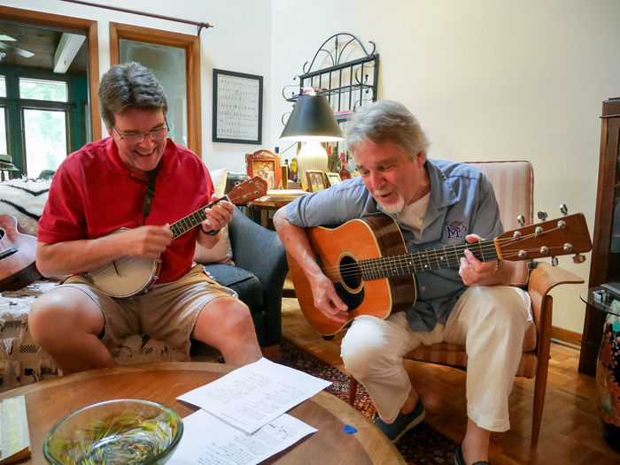 Smiling father and son playing guitar at home