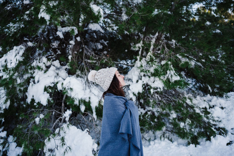 Woman in snowy mountain wrapped in blanket. winter