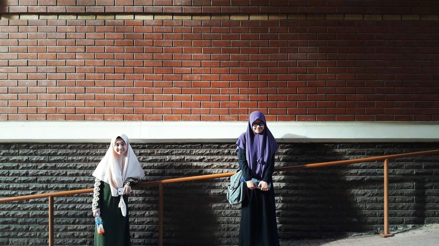 Young woman in traditional clothing standing against brick wall