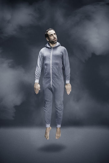 Full length of man levitating against gray background