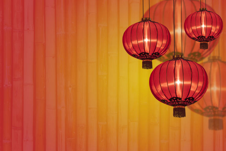 Low angle view of illuminated lantern hanging against orange wall
