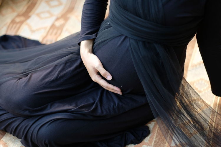 Maternity photo with the theme of black clothes and hands forming love on the stomach