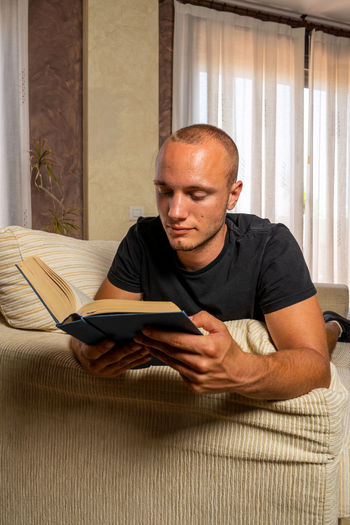Young man using mobile phone while sitting on sofa at home