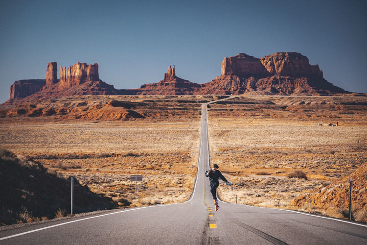 Girl is jumping on the road near forrest gump point, monument valley