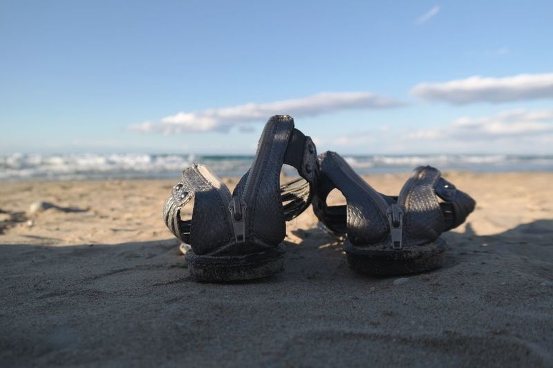 Close-up of footwear on sand at beach