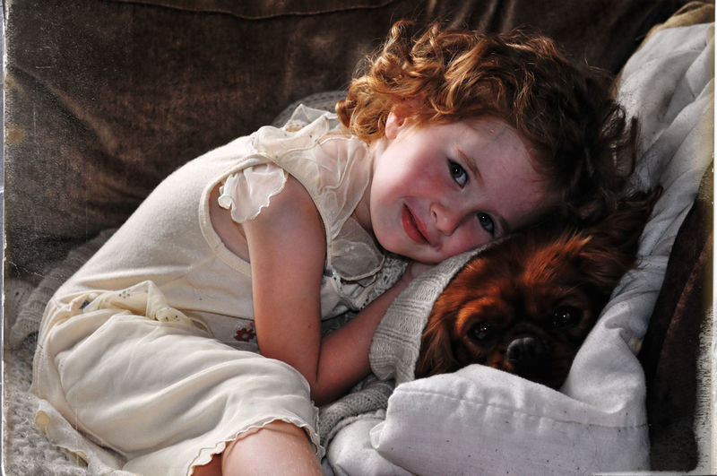 Portrait of girl with dog on bed at home
