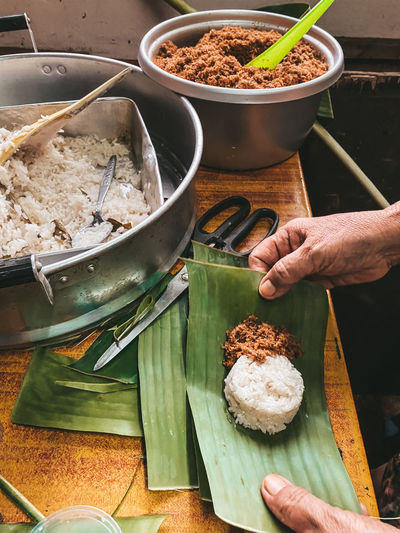 Midsection of person preparing malaysian food in kitchen on banana leaf