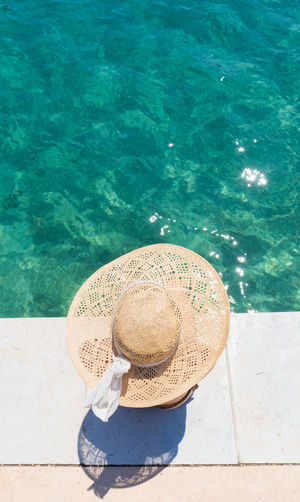 Directly above shot of woman wearing hat sitting at poolside