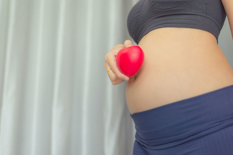 Midsection of woman holding strawberry while standing at home