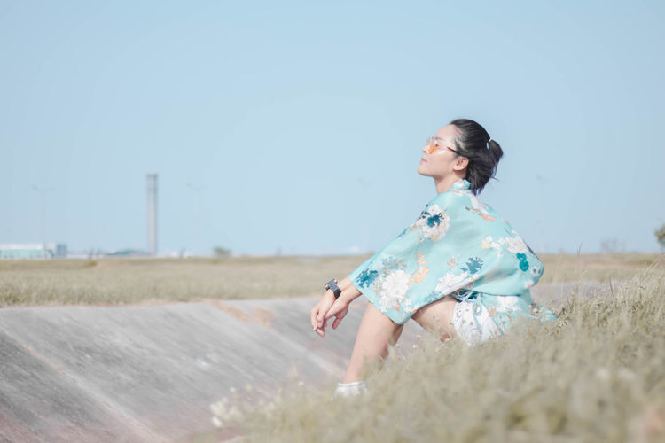 Full length of woman sitting on land against sky
