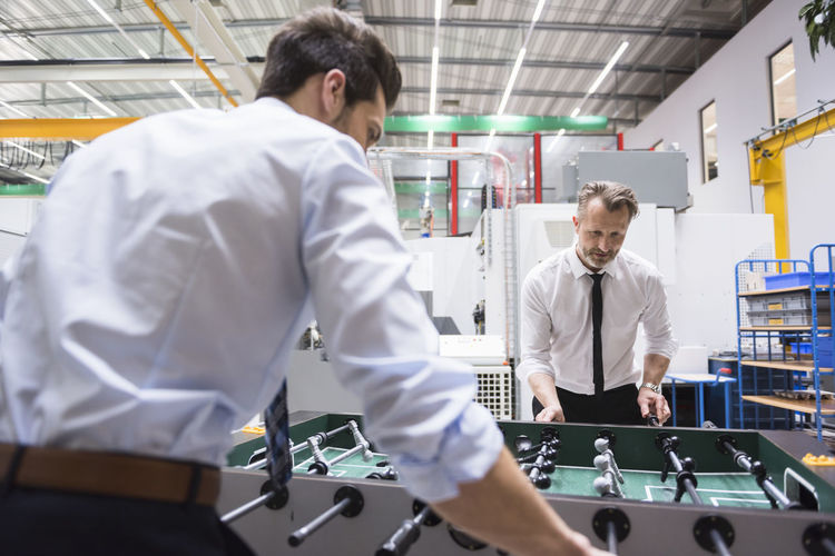 Two colleagues playing foosball in factory