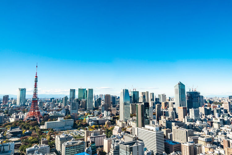 Aerial view of city buildings against blue sky