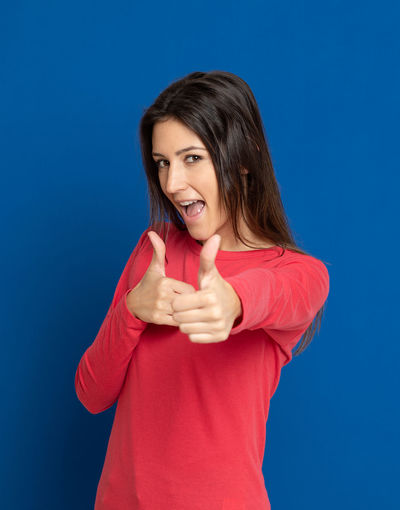 Portrait of a smiling young woman against blue background